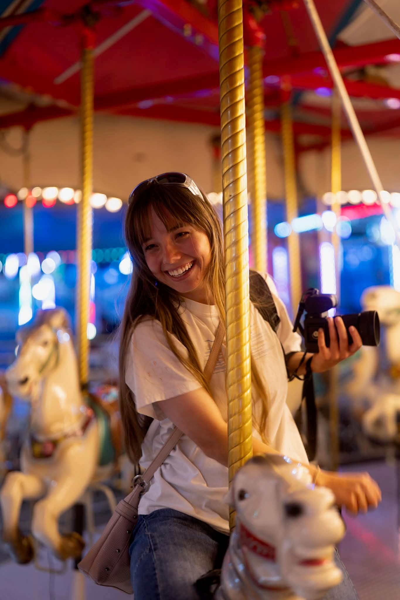 A photographer holding a camera on a brightly lit carousel.